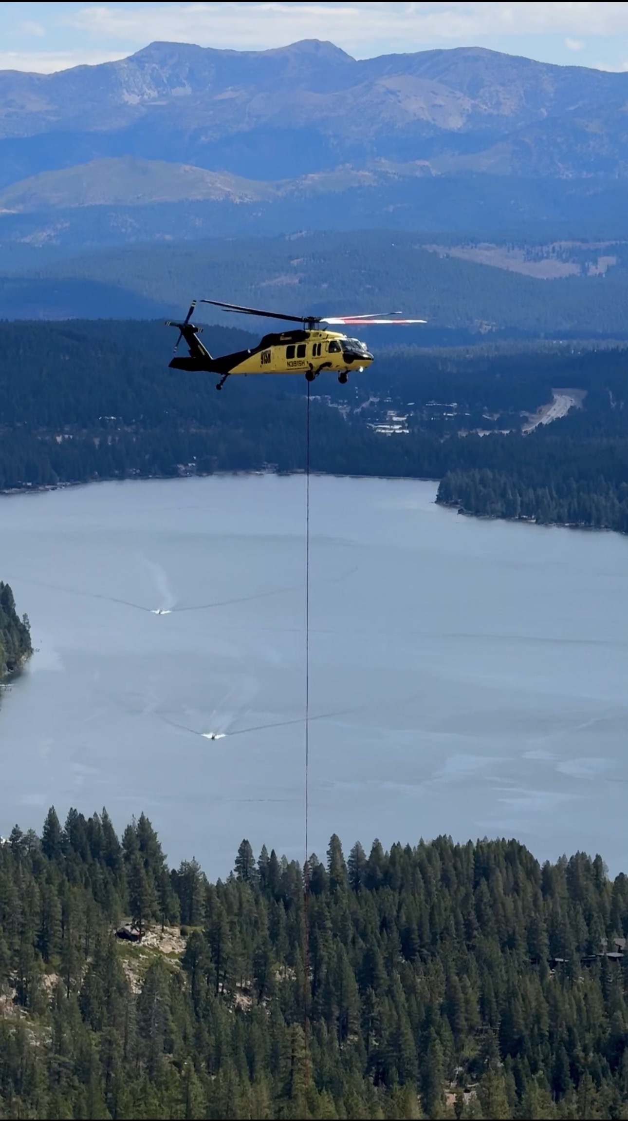 A UH-60 flying a long line over a mountain lake